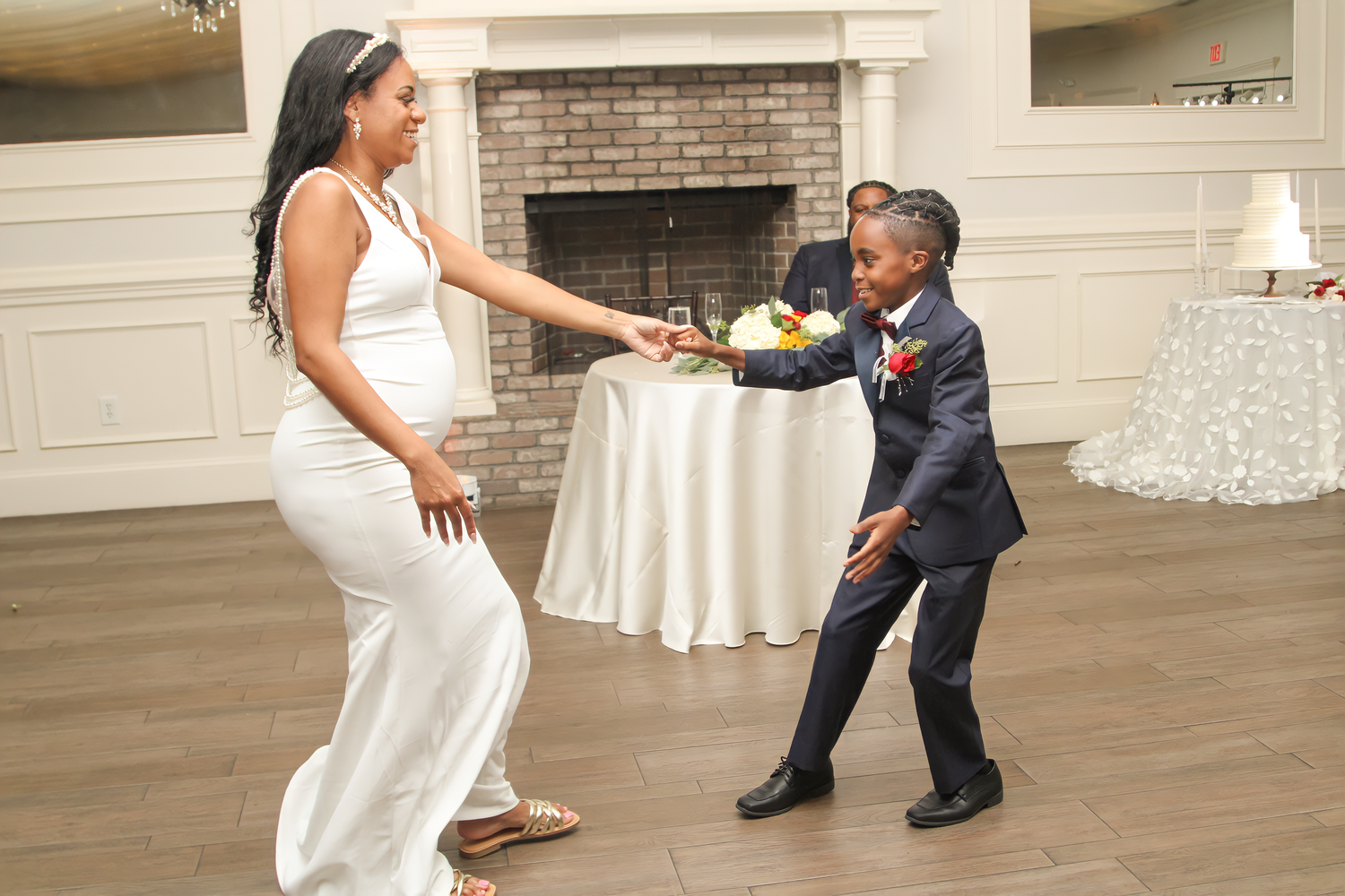 Wedding couple dances playfully on hardwood floor during reception celebration.