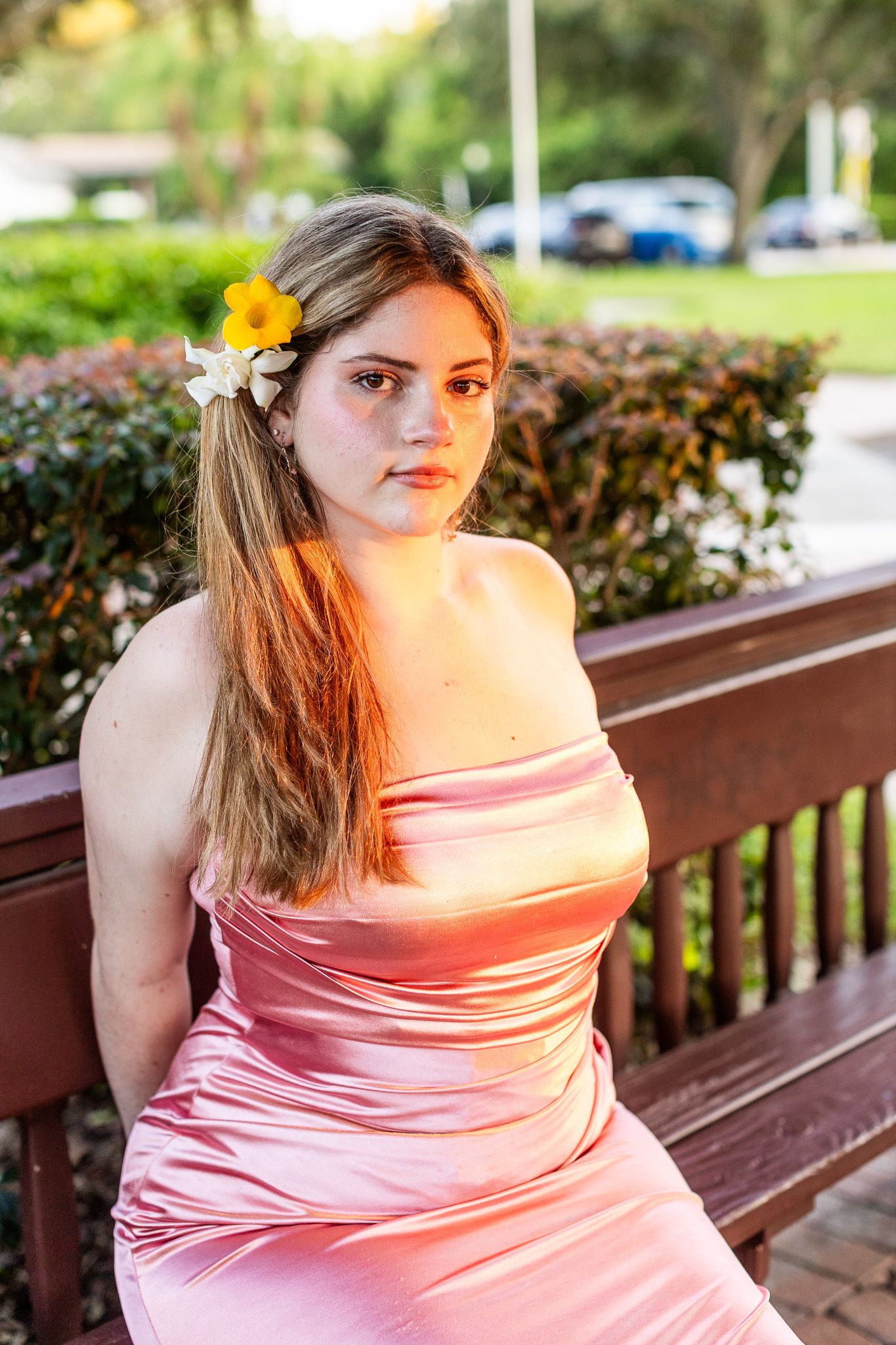 Pink satin dress with floral hair accessory in outdoor garden setting.
