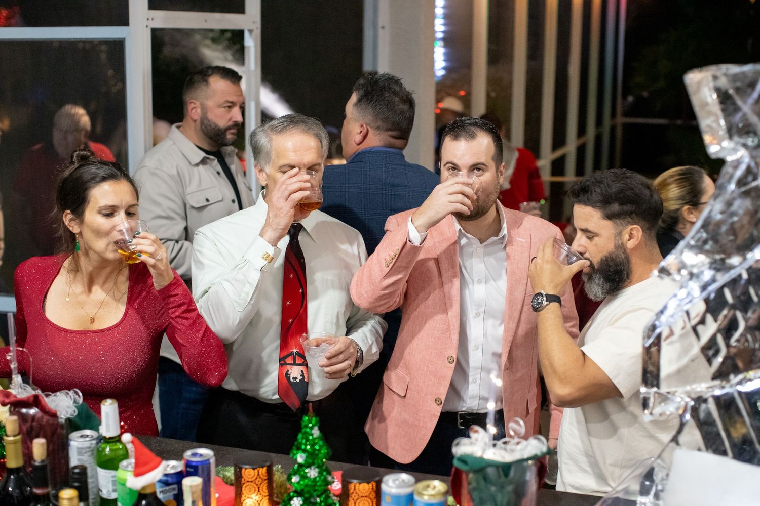 Group enjoying drinks at a bar with bottles and decorative elements in the background.