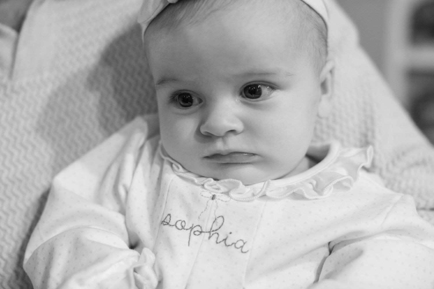 Close-up view of an infant wearing a white outfit against a light background.