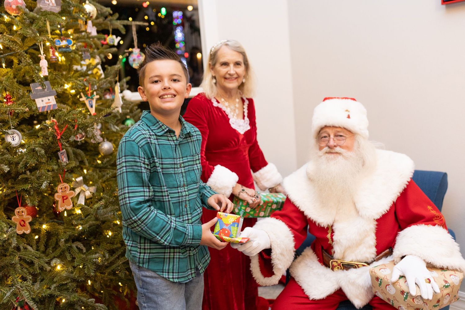 A festive holiday scene with Santa Claus seated by a decorated Christmas tree.