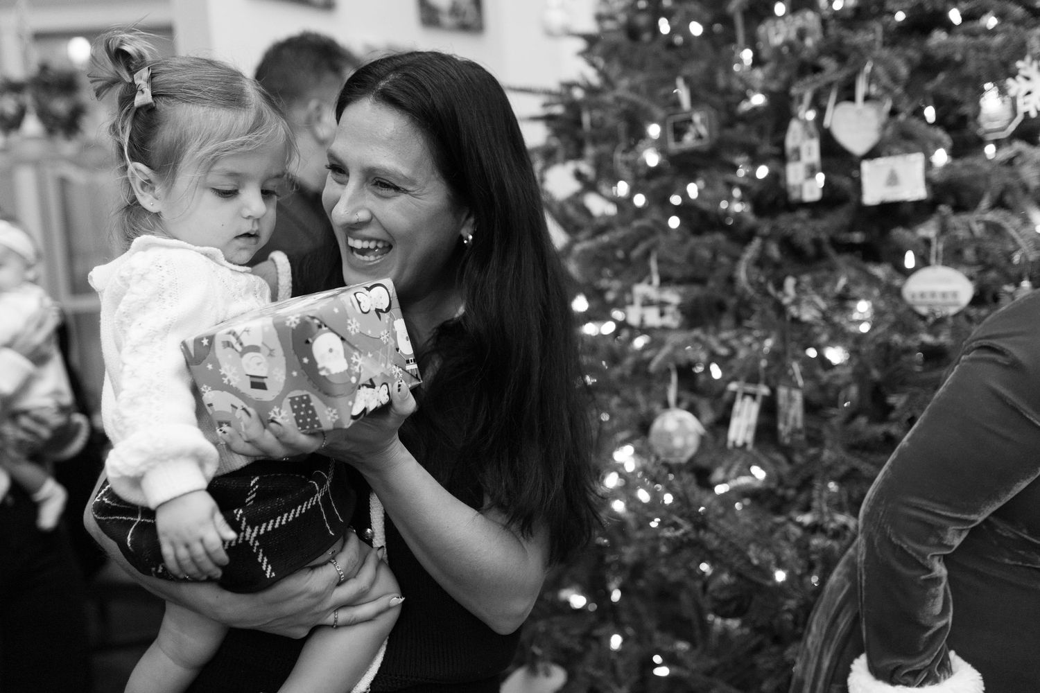 Black and white photo of parent and child sharing a joyful moment with Christmas presents.