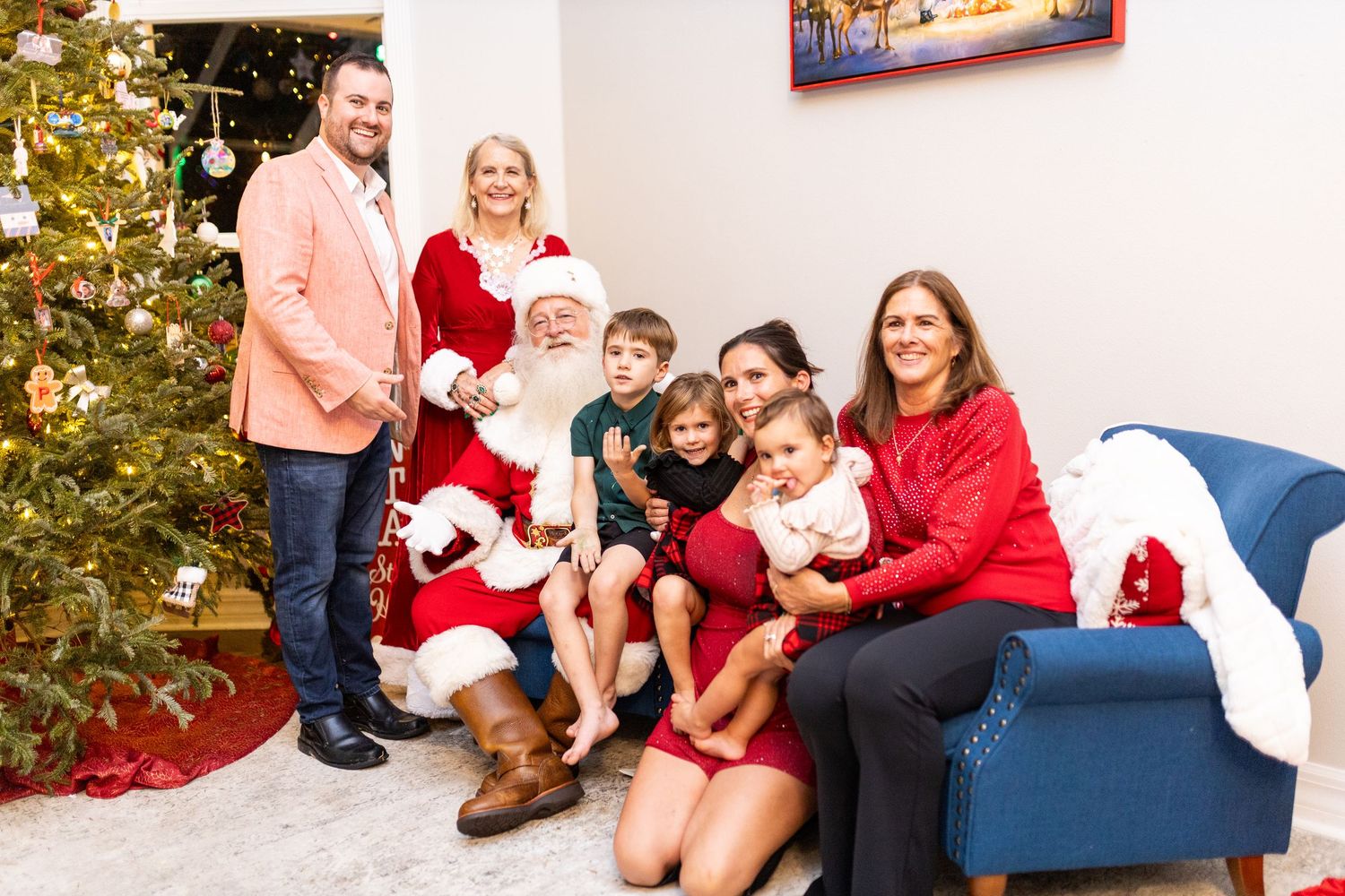 Christmas photo session featuring Santa Claus and family members in a decorated indoor setting.