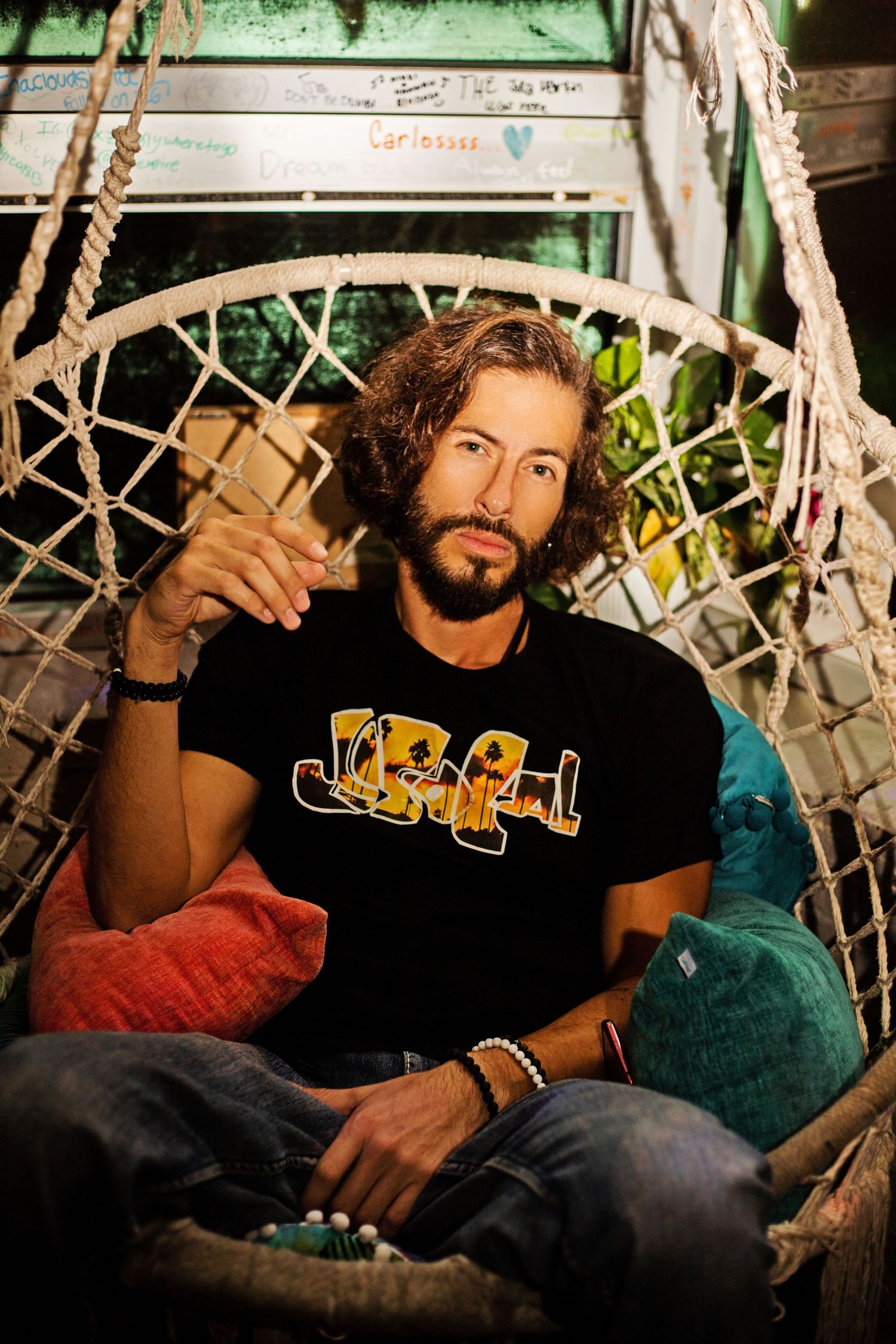 Person relaxing on cushions in casual attire against decorative background.