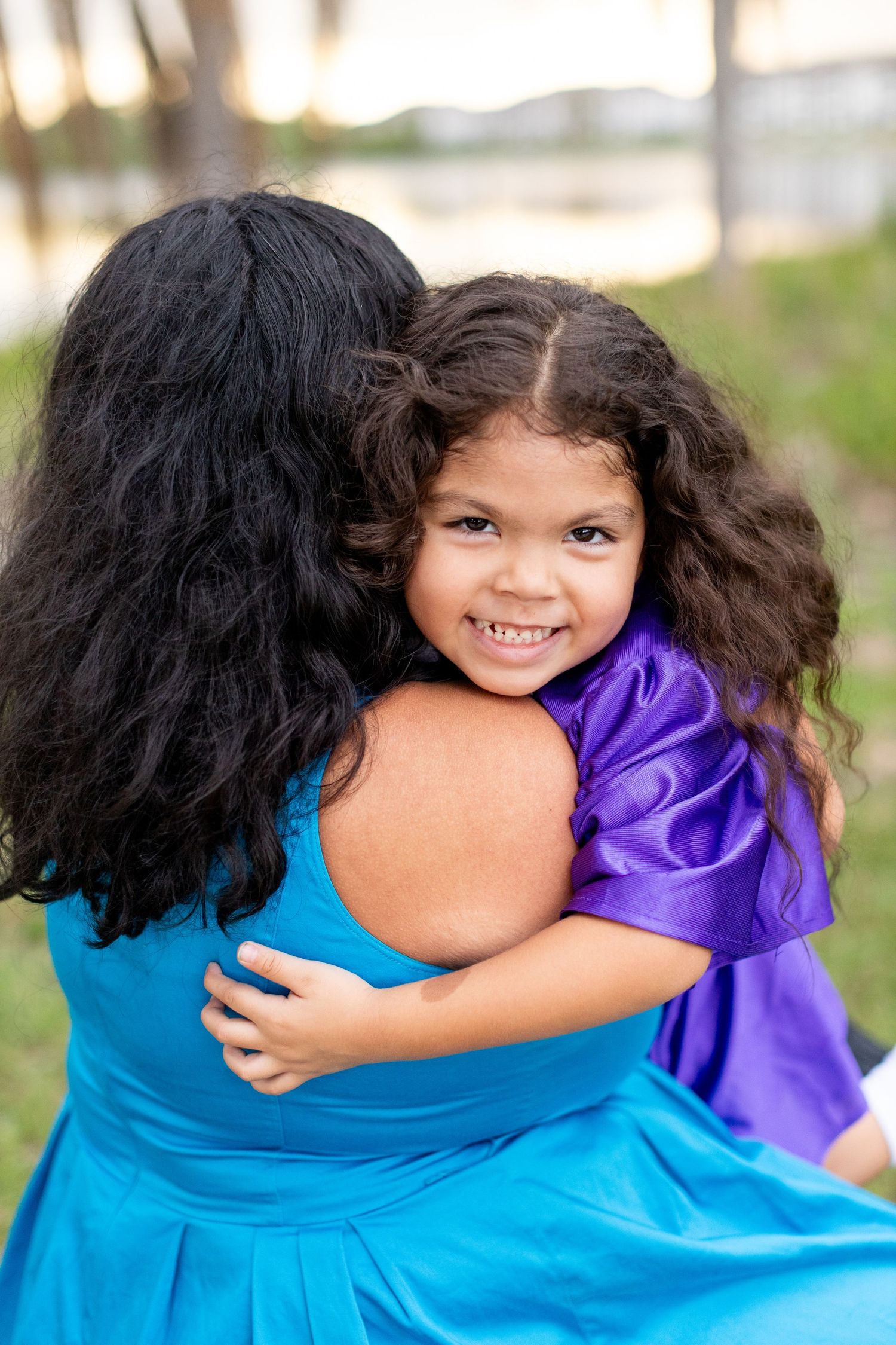 Heartwarming embrace between two people, one wearing bright blue and one in purple graduation attire.