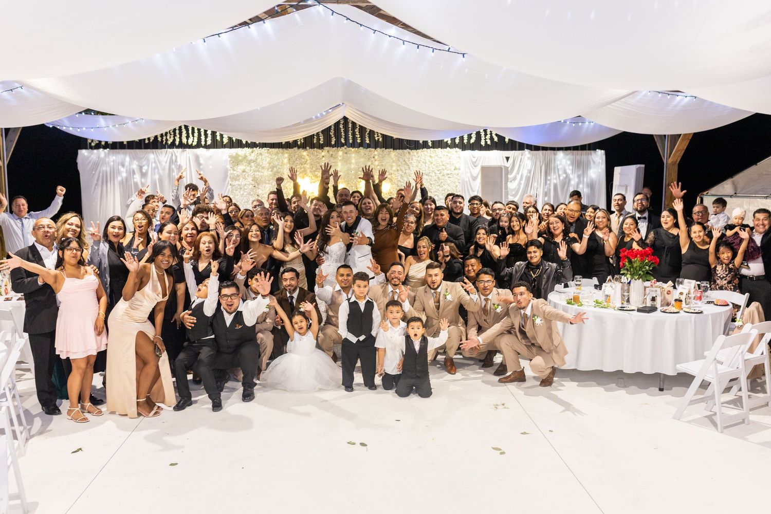 Large group panorama of wedding guests gathered for a celebratory photo in the reception venue.