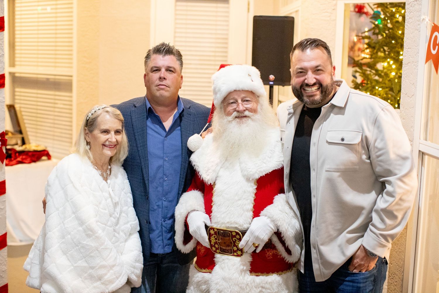 Holiday gathering with Santa Claus and guests posing for a cheerful photo.