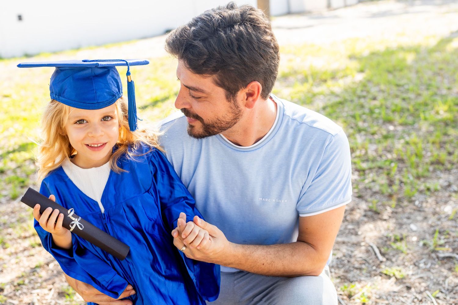 A heartwarming graduation moment shared between graduate in blue and companion in casual wear outdoors.