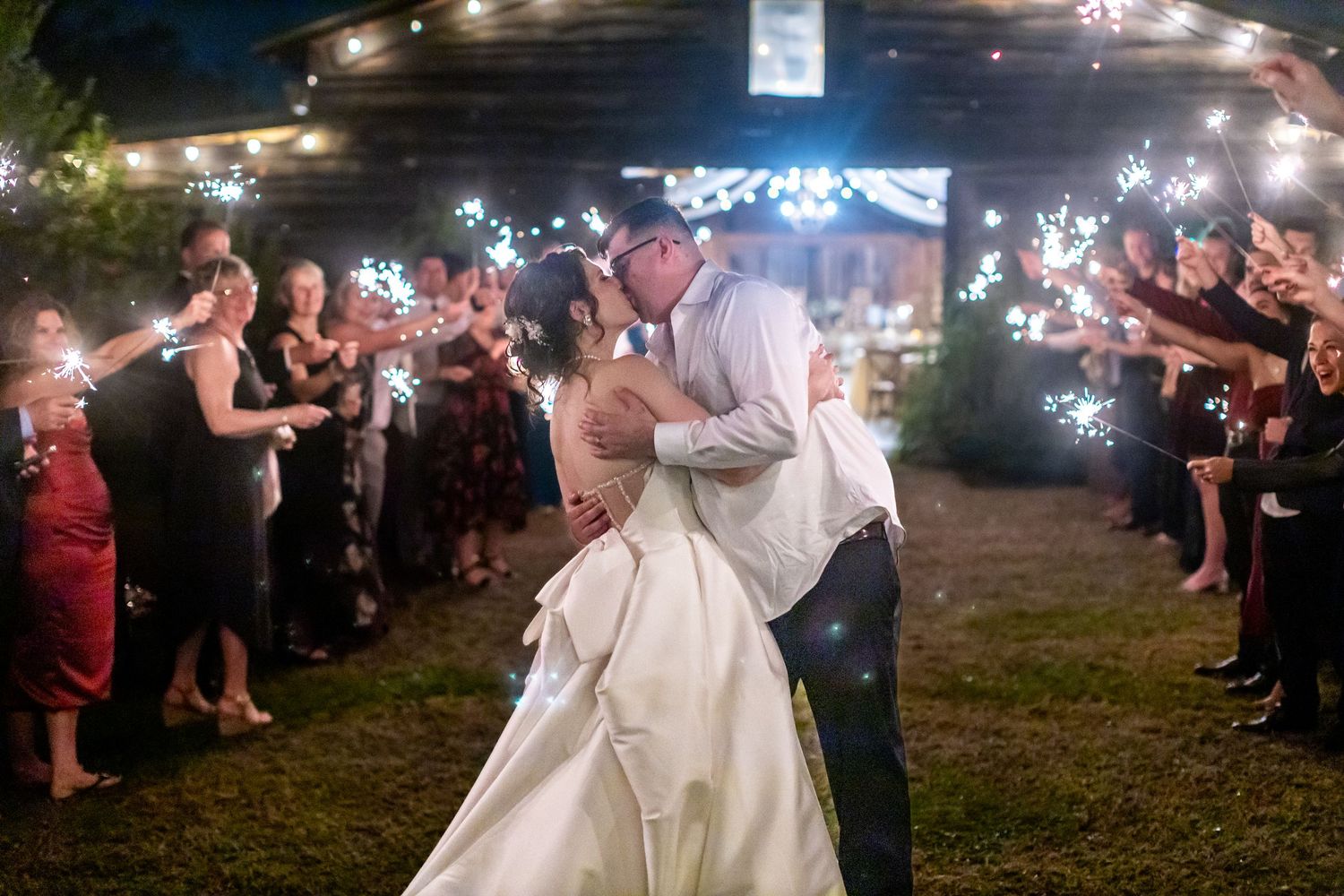 Sparkler exit celebration with couple walking through glowing sparkler tunnel at night.