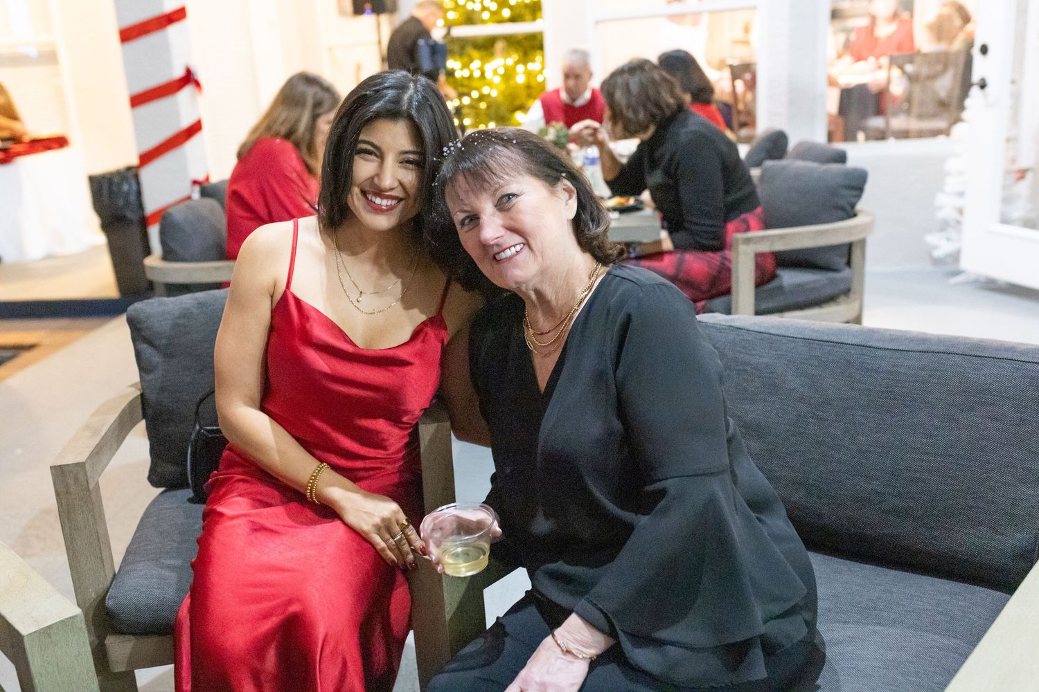 Social gathering with people in formal attire seated on grey couches.