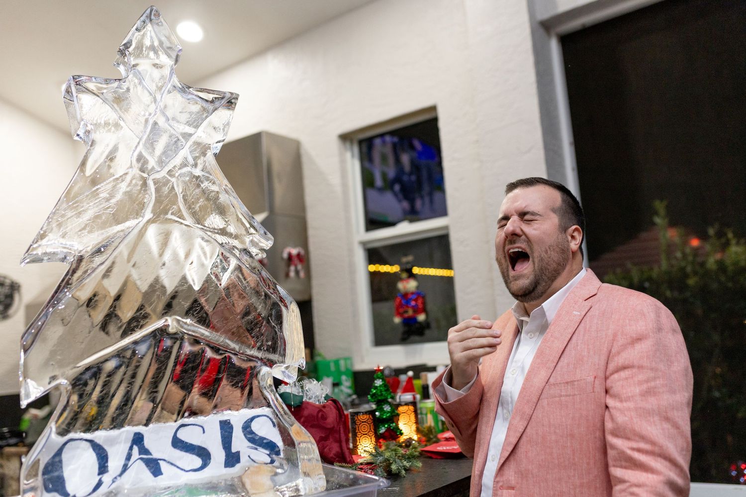 Someone in a pink jacket holds up a large clear decorative piece near an Oasis sign.