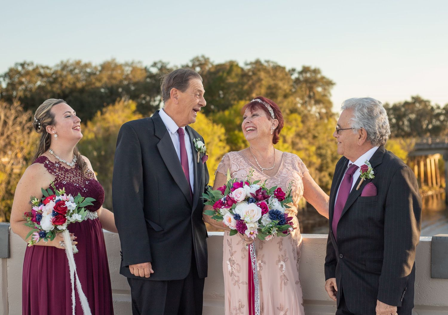 Wedding party in burgundy and black attire posing outdoors.