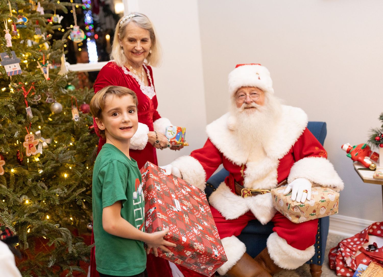 A decorated Christmas tree provides a festive backdrop for Santa meeting with children.