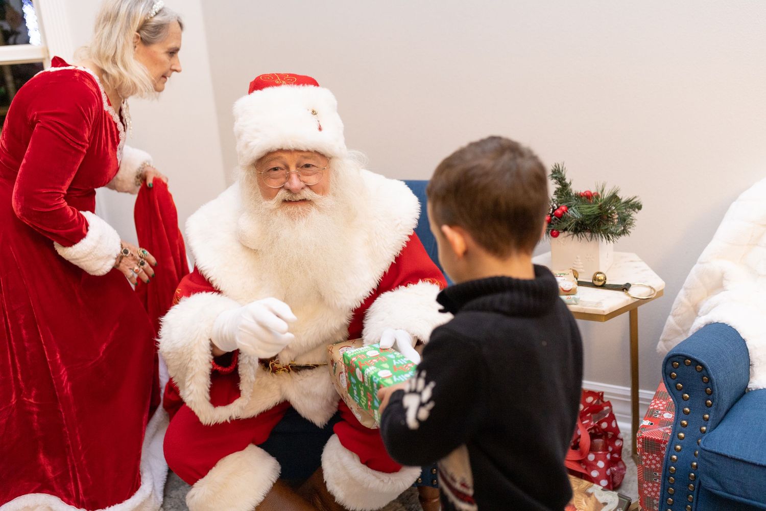 Santa Claus greets young visitors beside a decorated Christmas tree during holiday celebrations.