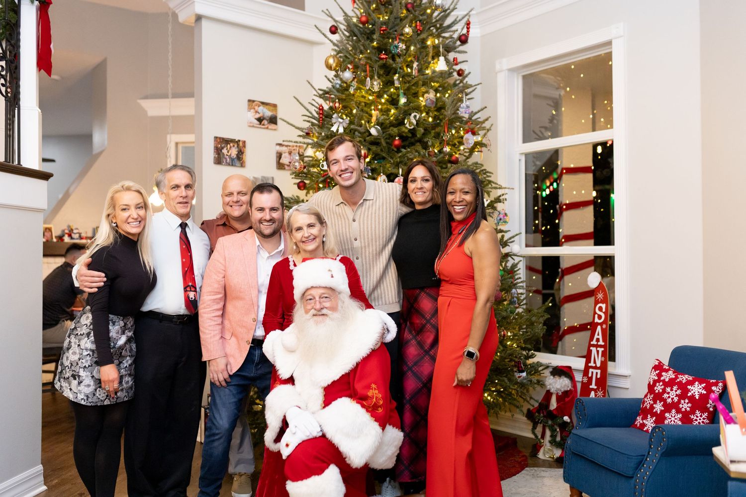 Christmas gathering in living room with decorated tree and guests enjoying the festivities.