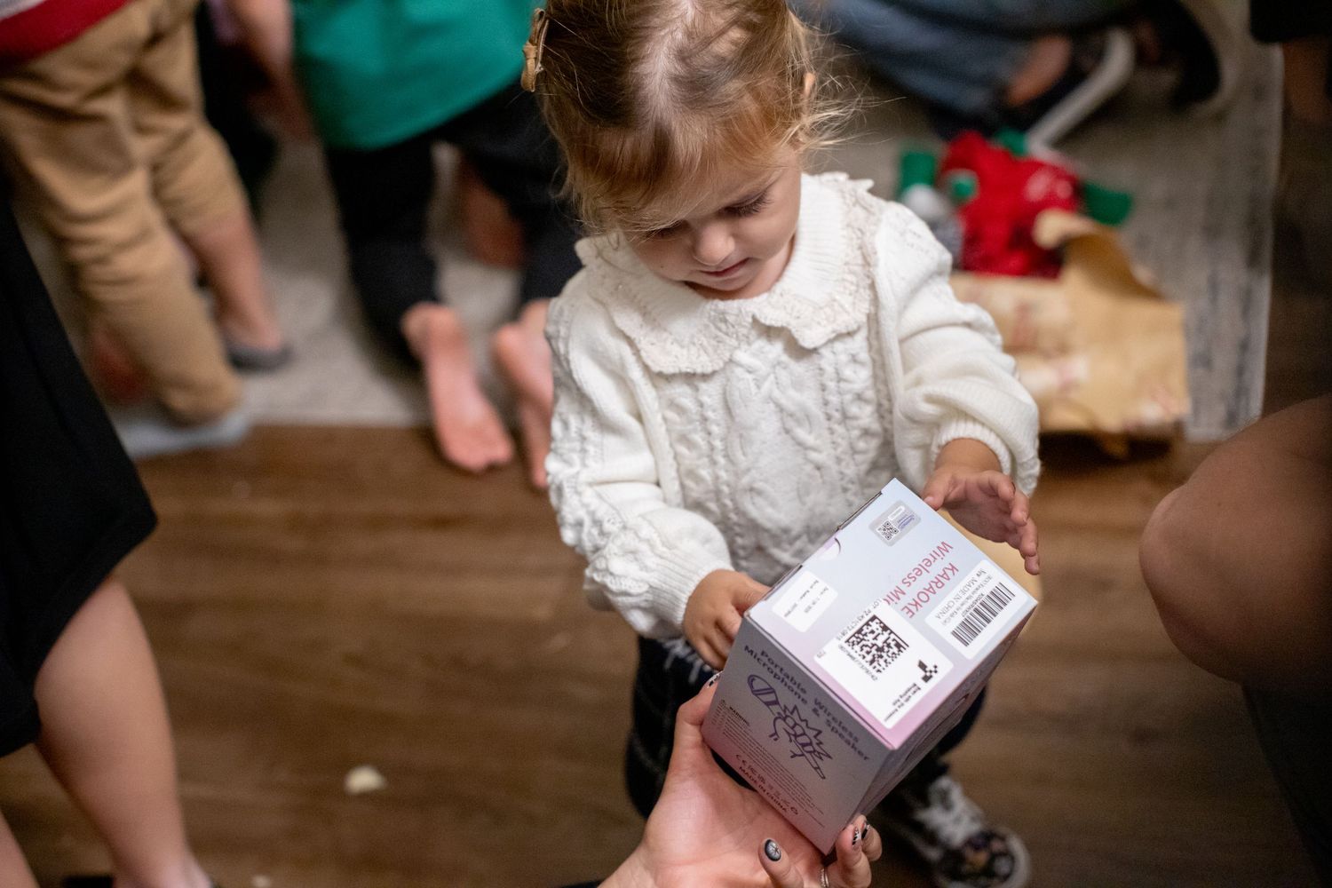 A small child examines a gift box during a holiday celebration.