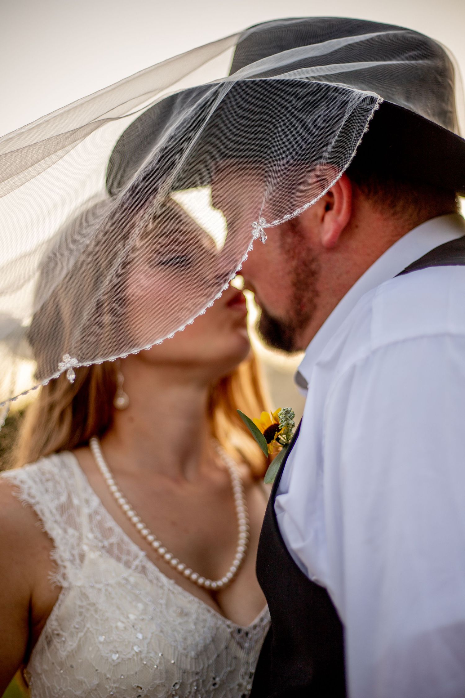 Close-up sequence of a romantic wedding kiss with pearl necklace and veil details.