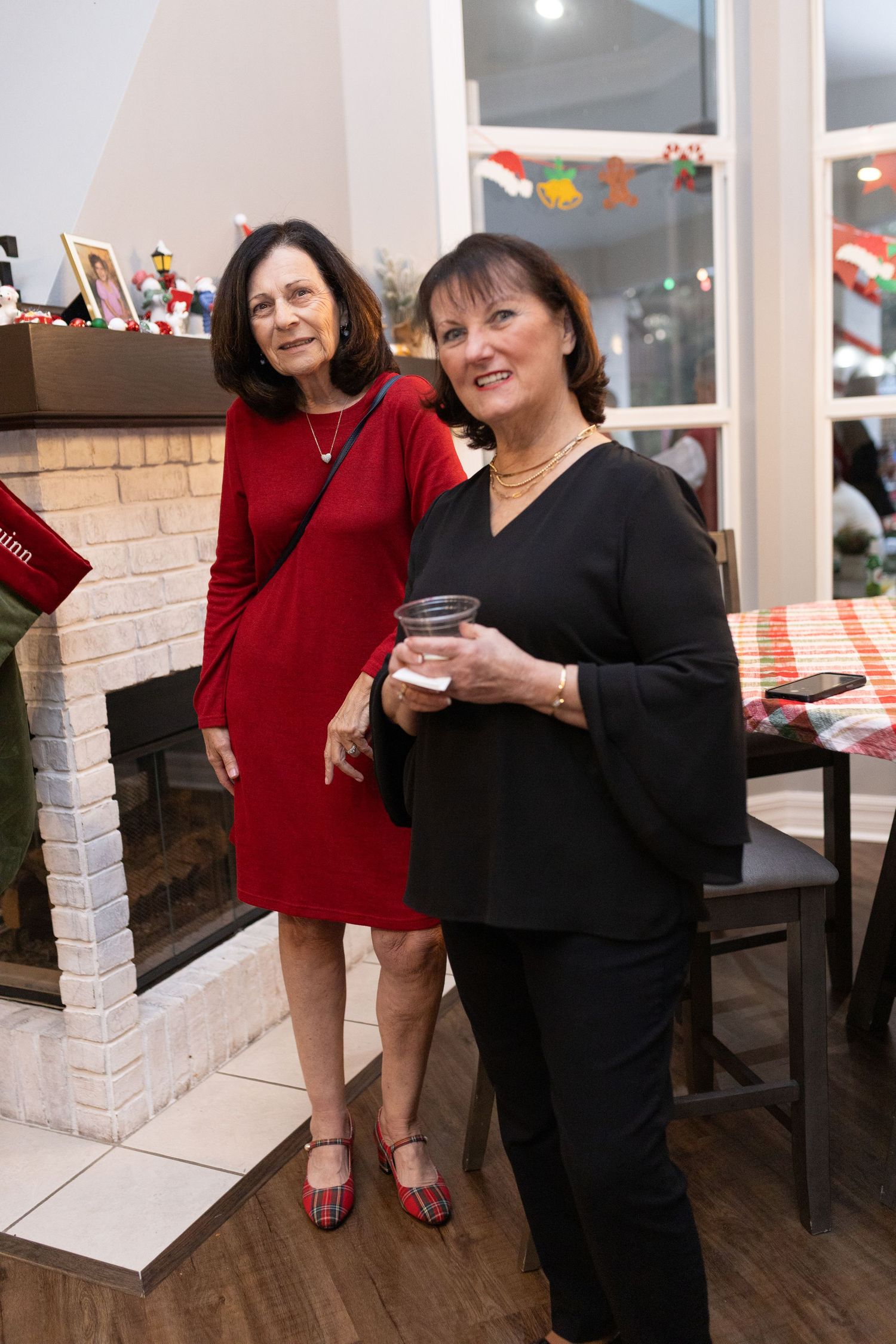 People mingling near a brick fireplace at a holiday gathering.
