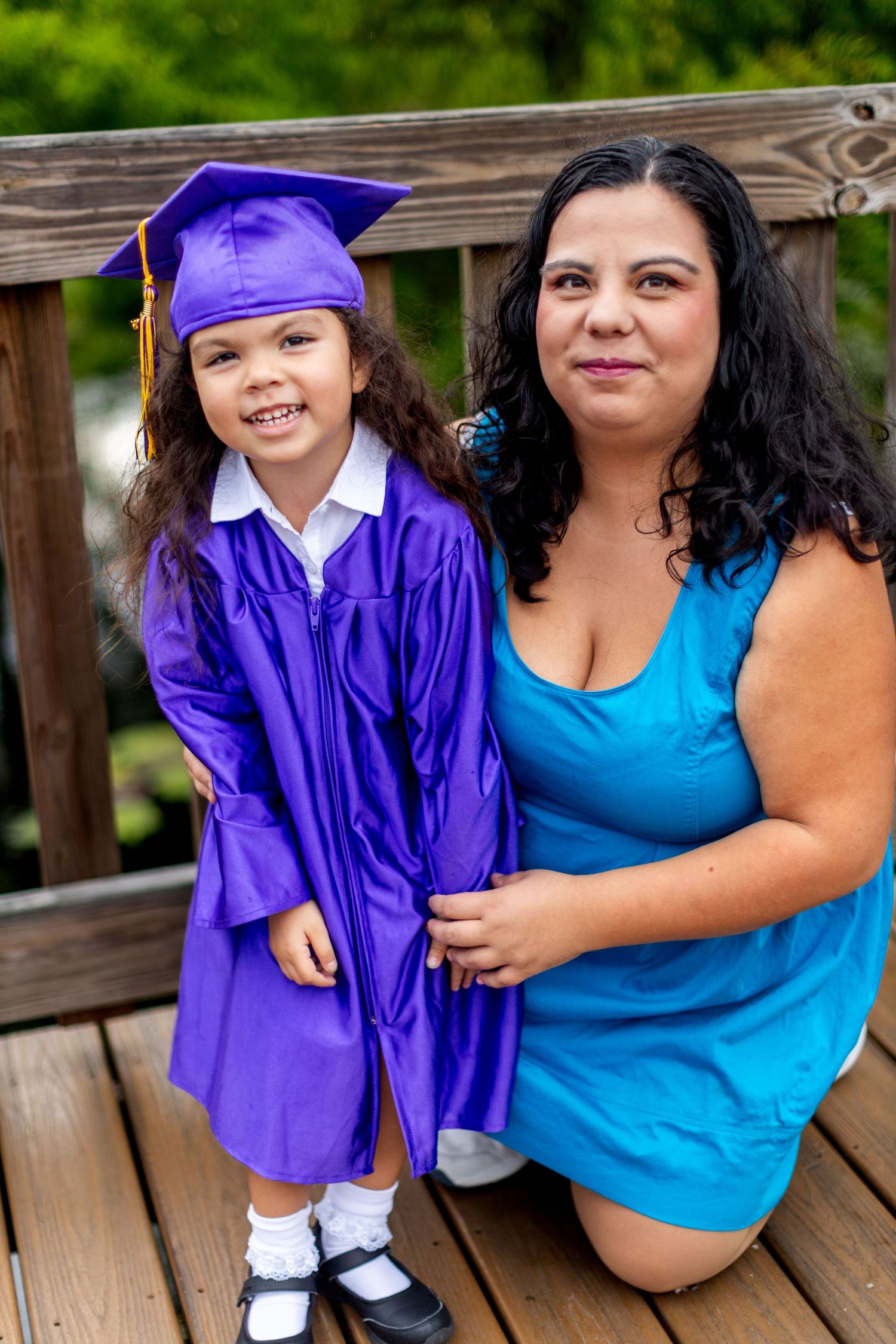 Graduation celebration moment captured on wooden deck with bright smiles and blue attire.