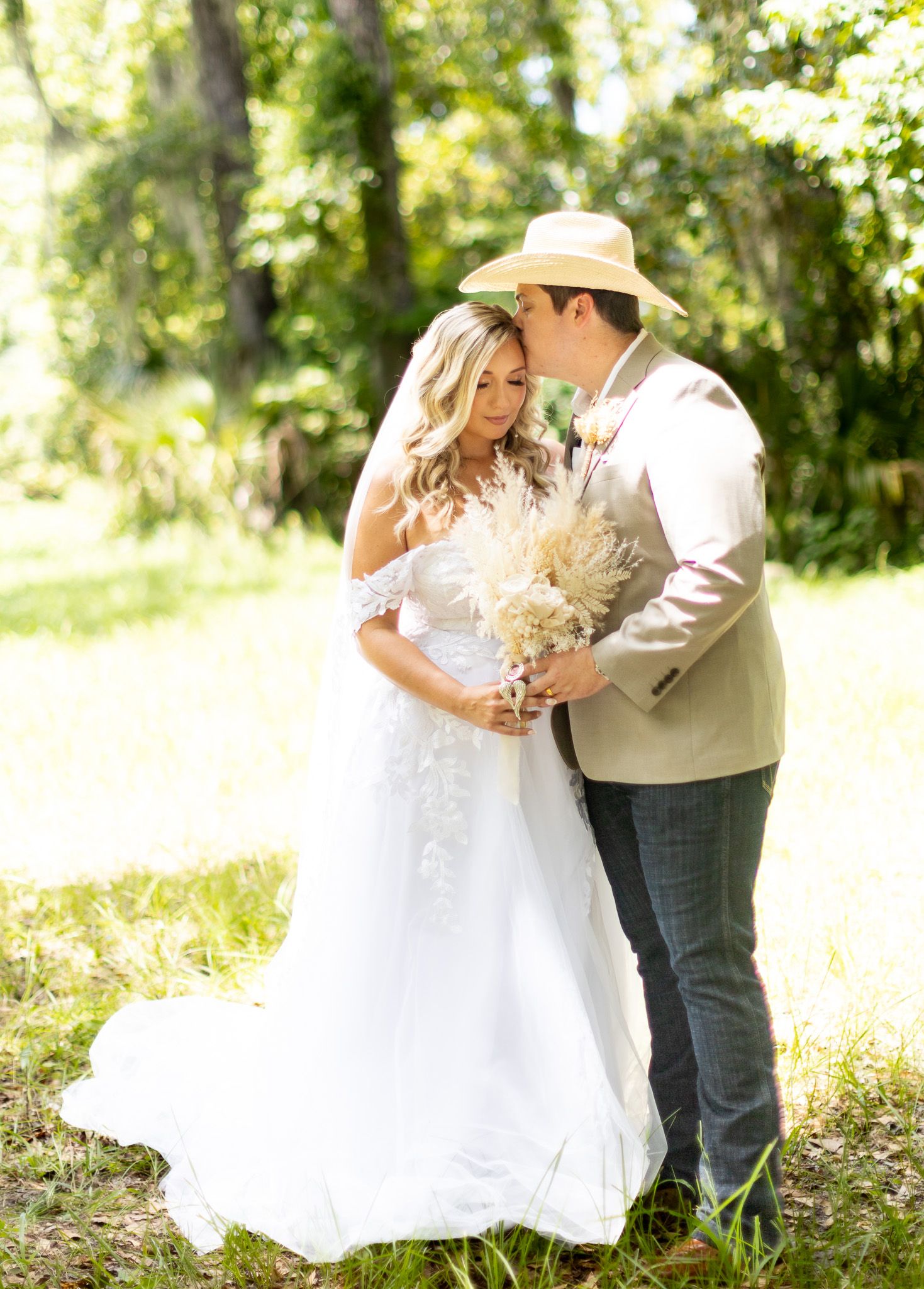 Romantic wedding photos in a sunlit field with white dress and cowboy hat.