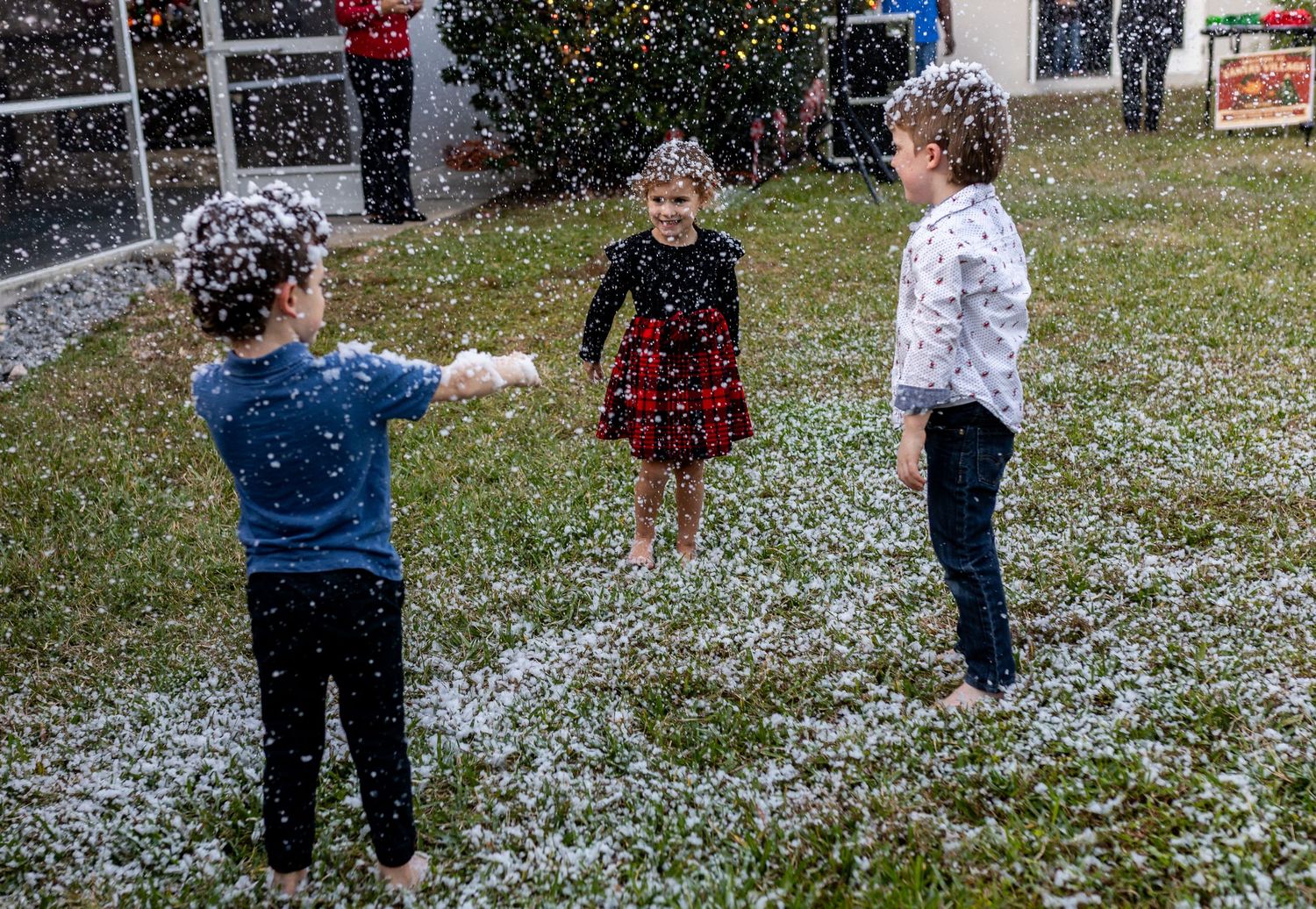 Guests enjoying artificial snow during outdoor winter party celebration.