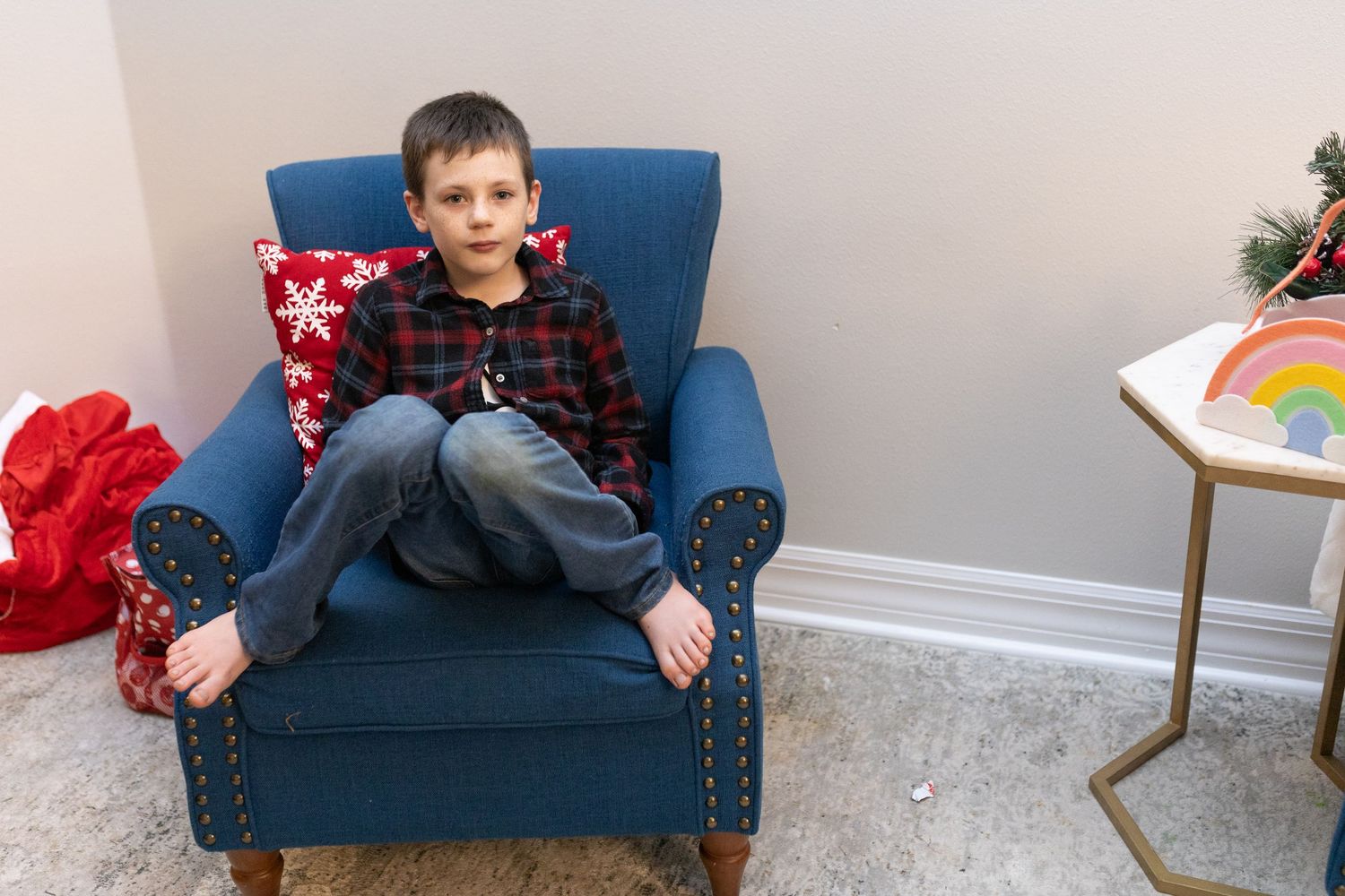 A child sits comfortably on a navy blue armchair in a decorated room.