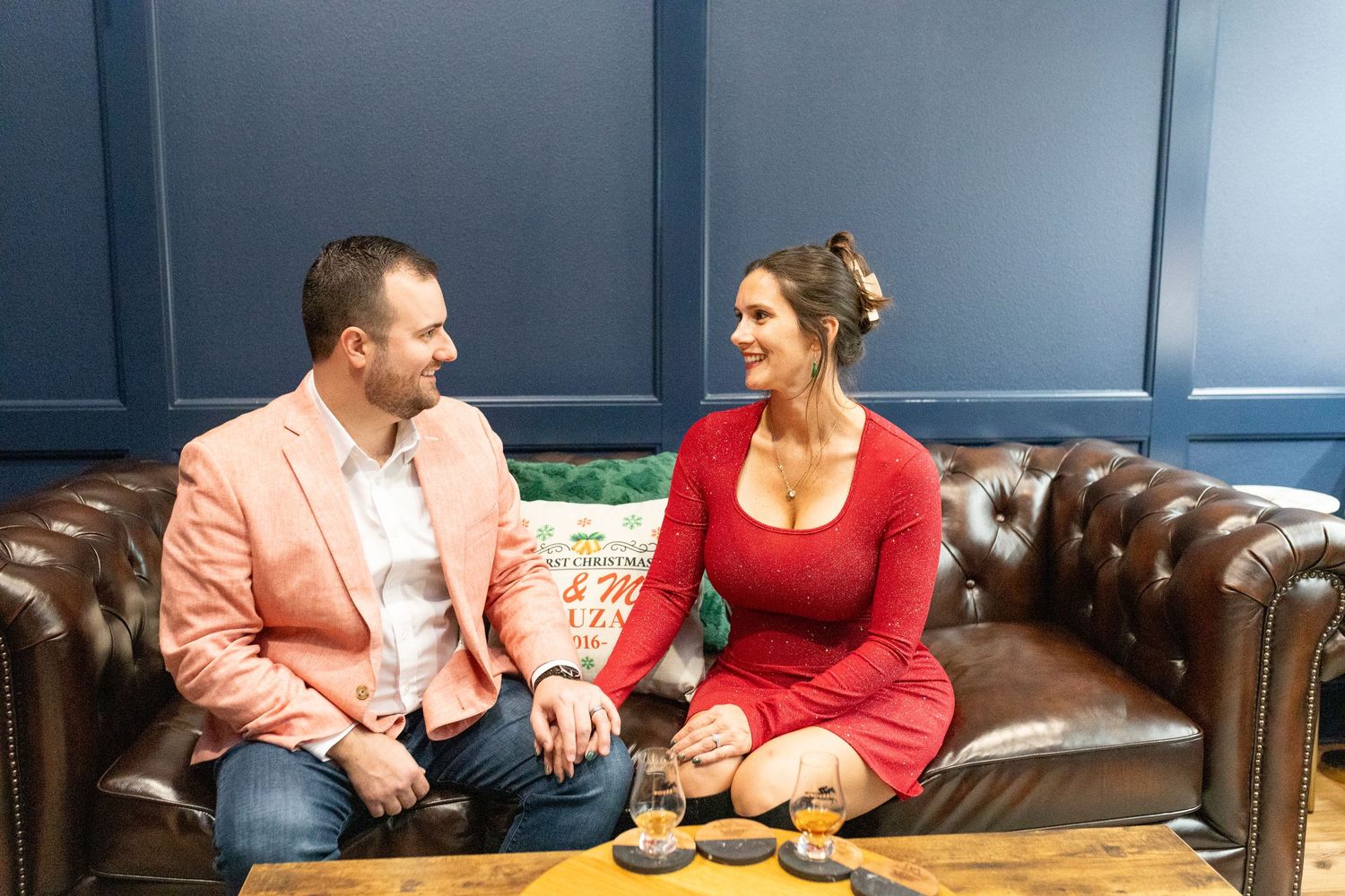 Couple having drinks while relaxing on leather couch in stylish bar setting.