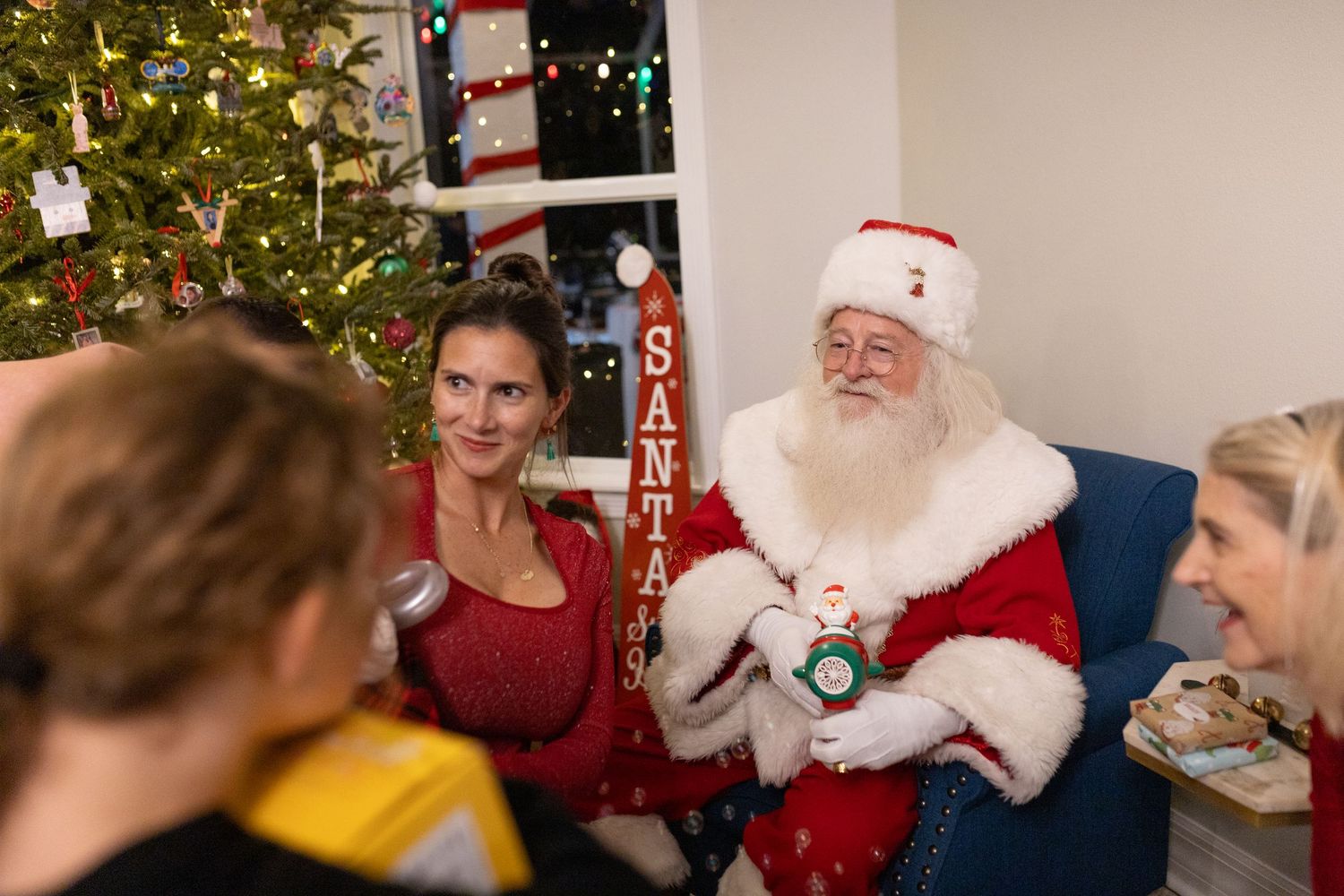 Santa Claus engages in conversation during a Christmas photo session near a decorated tree.