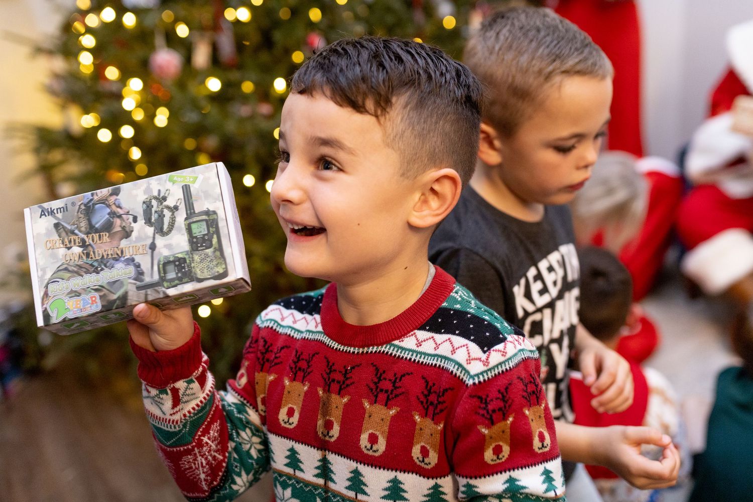 Holiday celebration with decorated Christmas trees and festive decorations in the background.