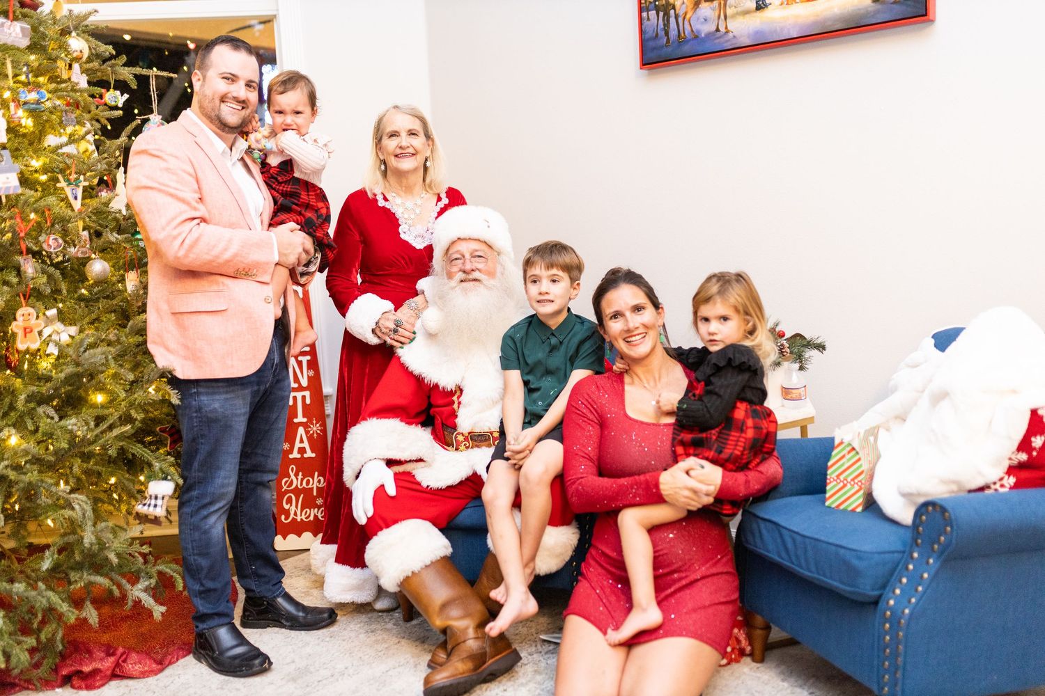 Christmas photoshoot featuring Santa Claus and family members in coordinated red outfits.