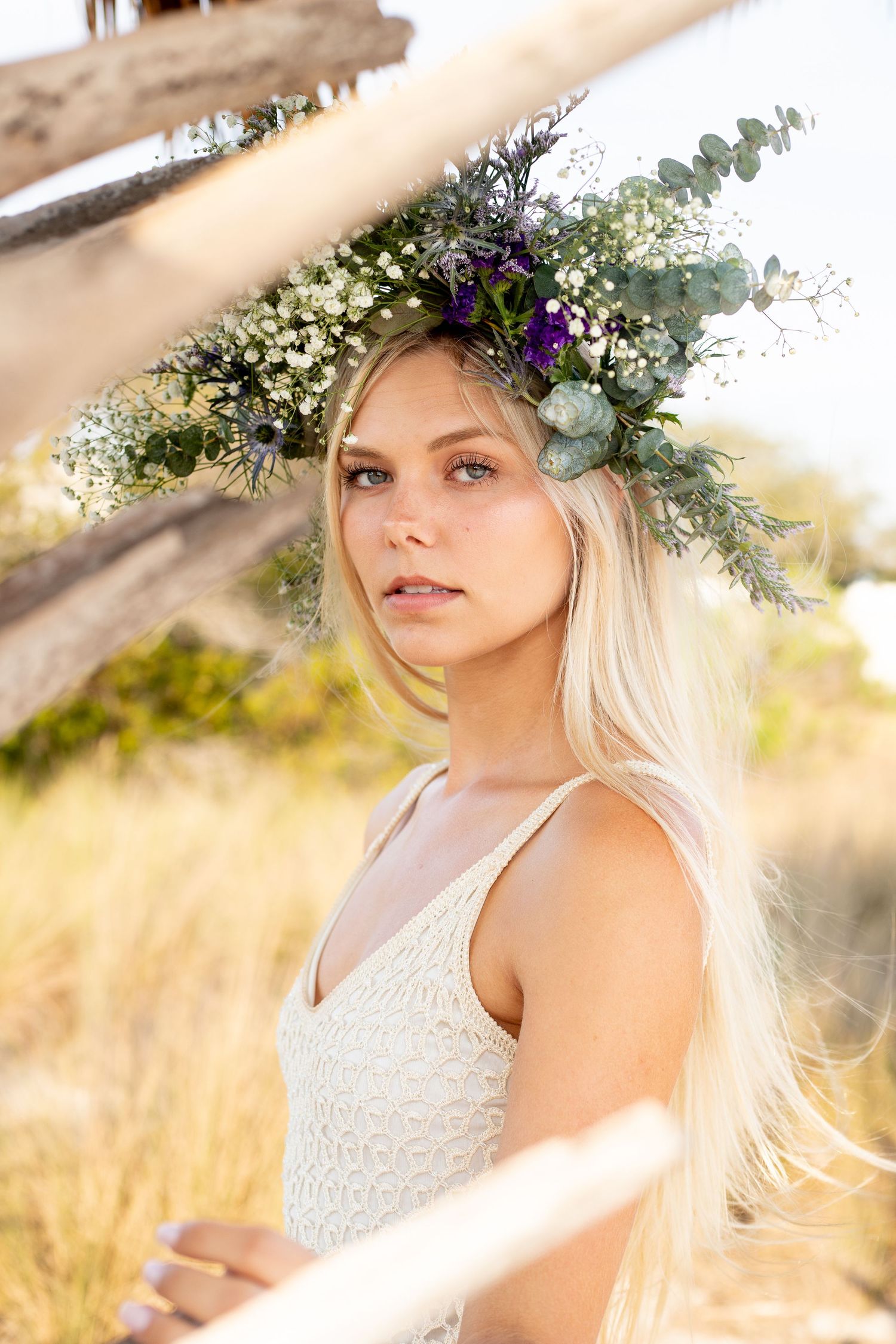 Bohemian style portrait with floral crown against natural summer backdrop.