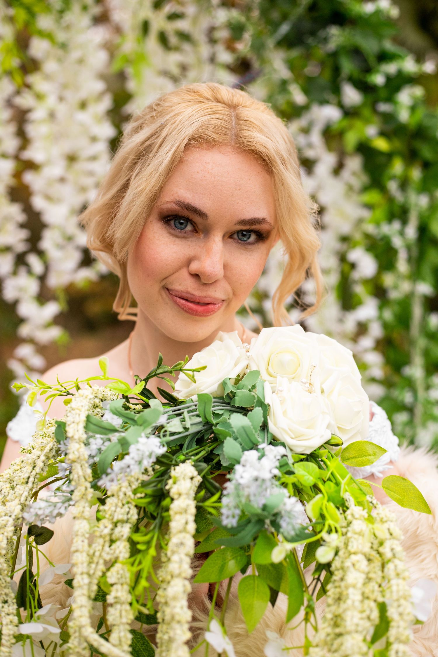 Elegant bridal portrait featuring a cascading white and green floral bouquet with delicate hanging flowers.