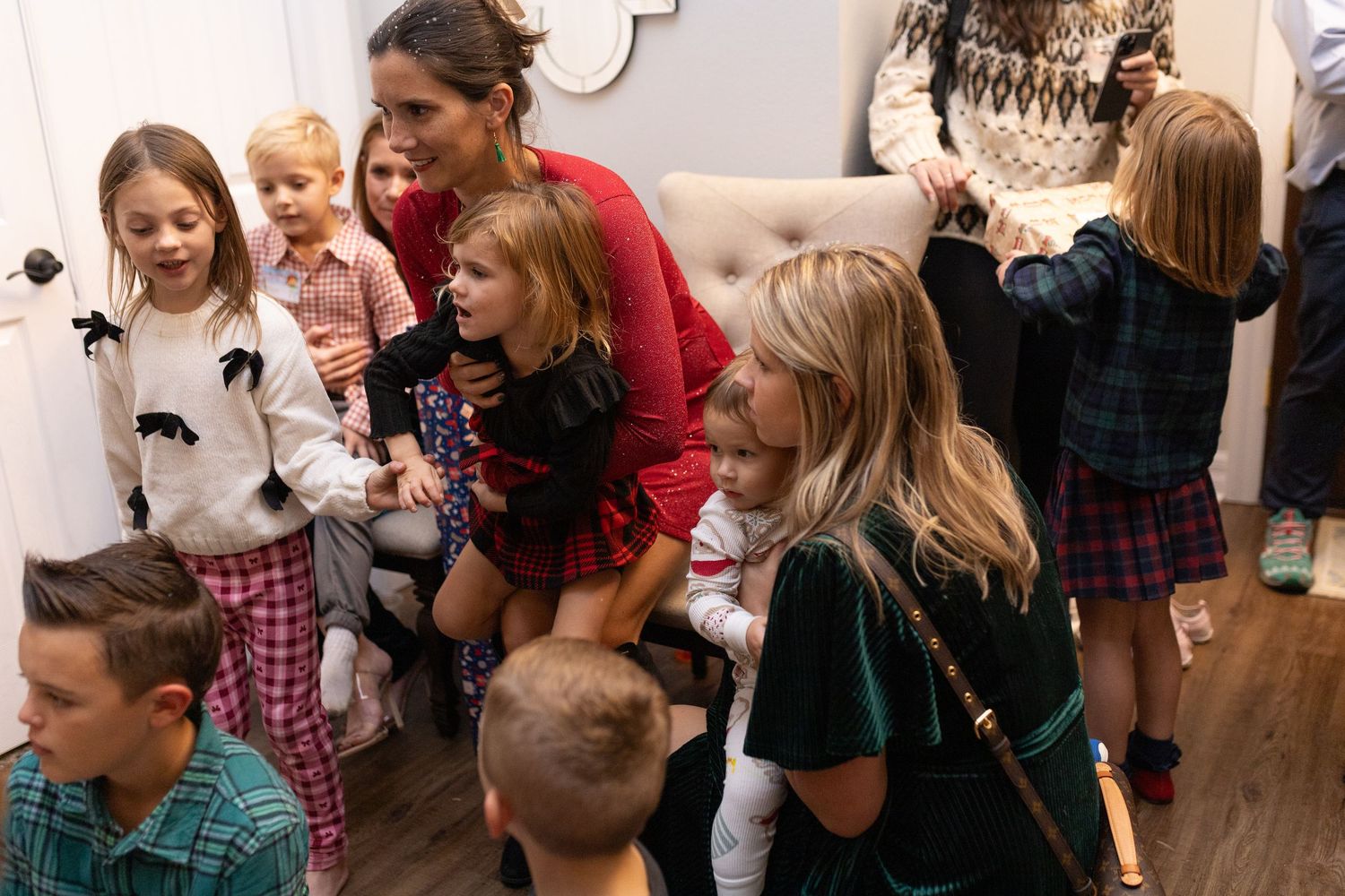 Group of people gathered at a holiday party with decorative elements visible in the background.