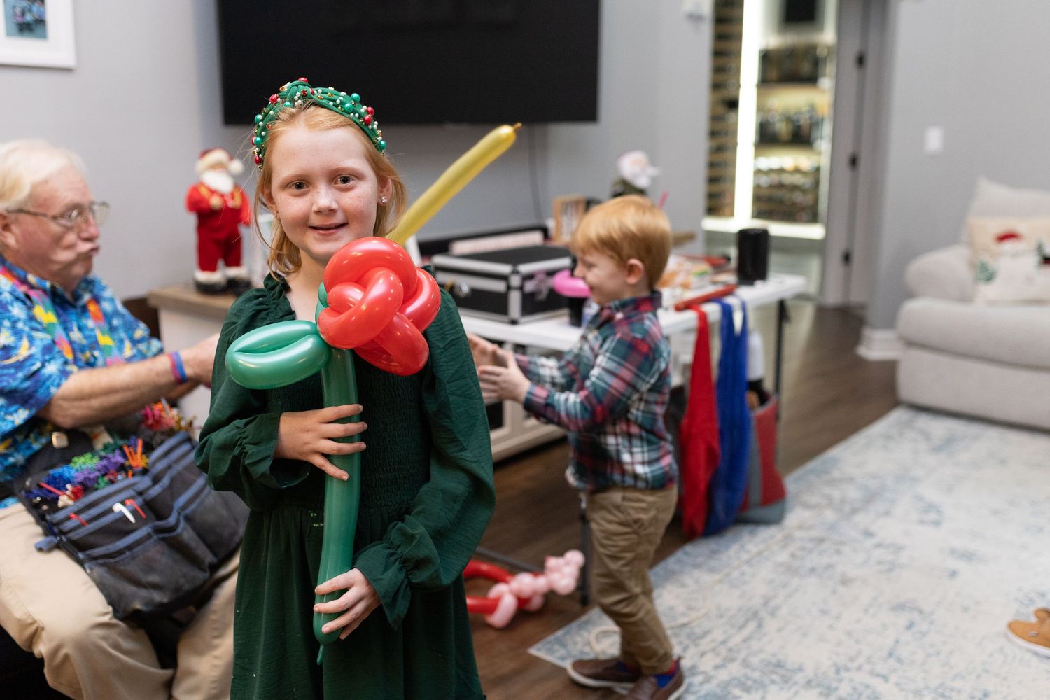 Children and adults enjoy holiday festivities in a living room decorated for Christmas.