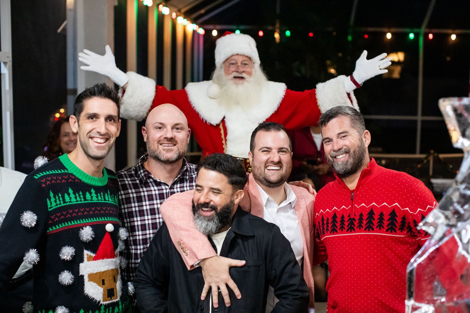 Friends celebrating at a nighttime holiday party with festive decorations.