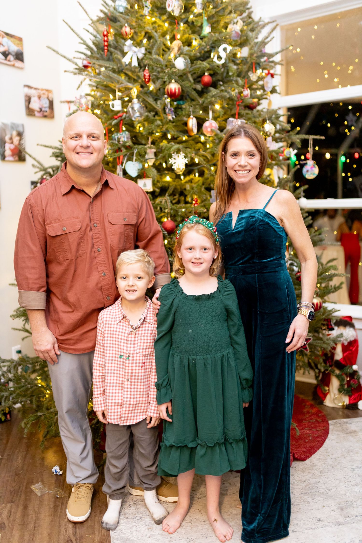 Group photo in front of decorated Christmas tree with matching brown and green holiday outfits.