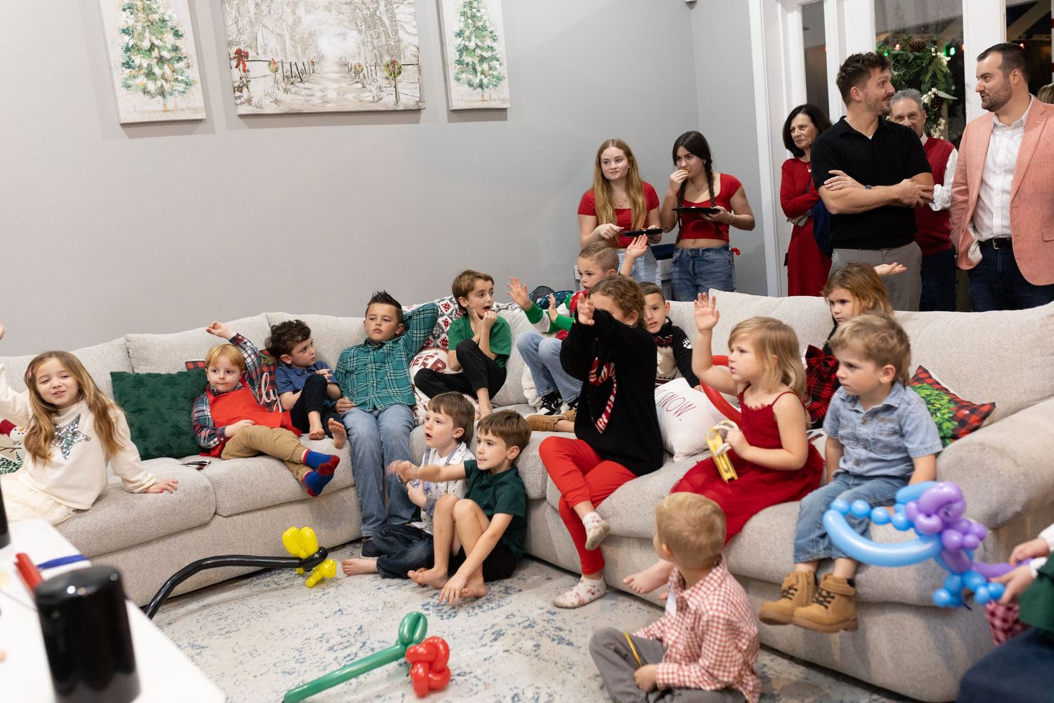 A group watches entertainment in a living room decorated with holiday artwork on the walls.