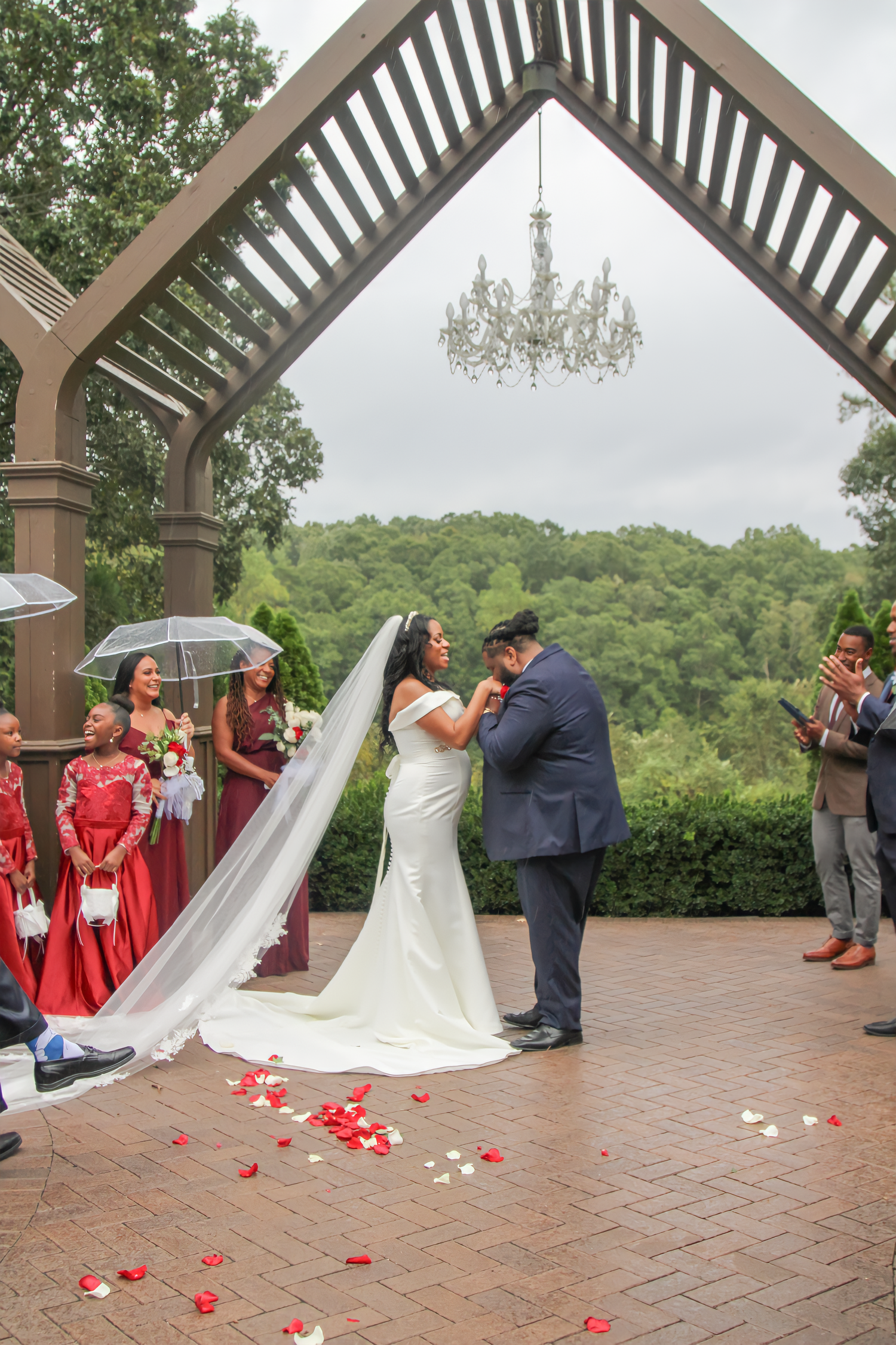 A wedding ceremony taking place under an elegant pergola with a crystal chandelier.