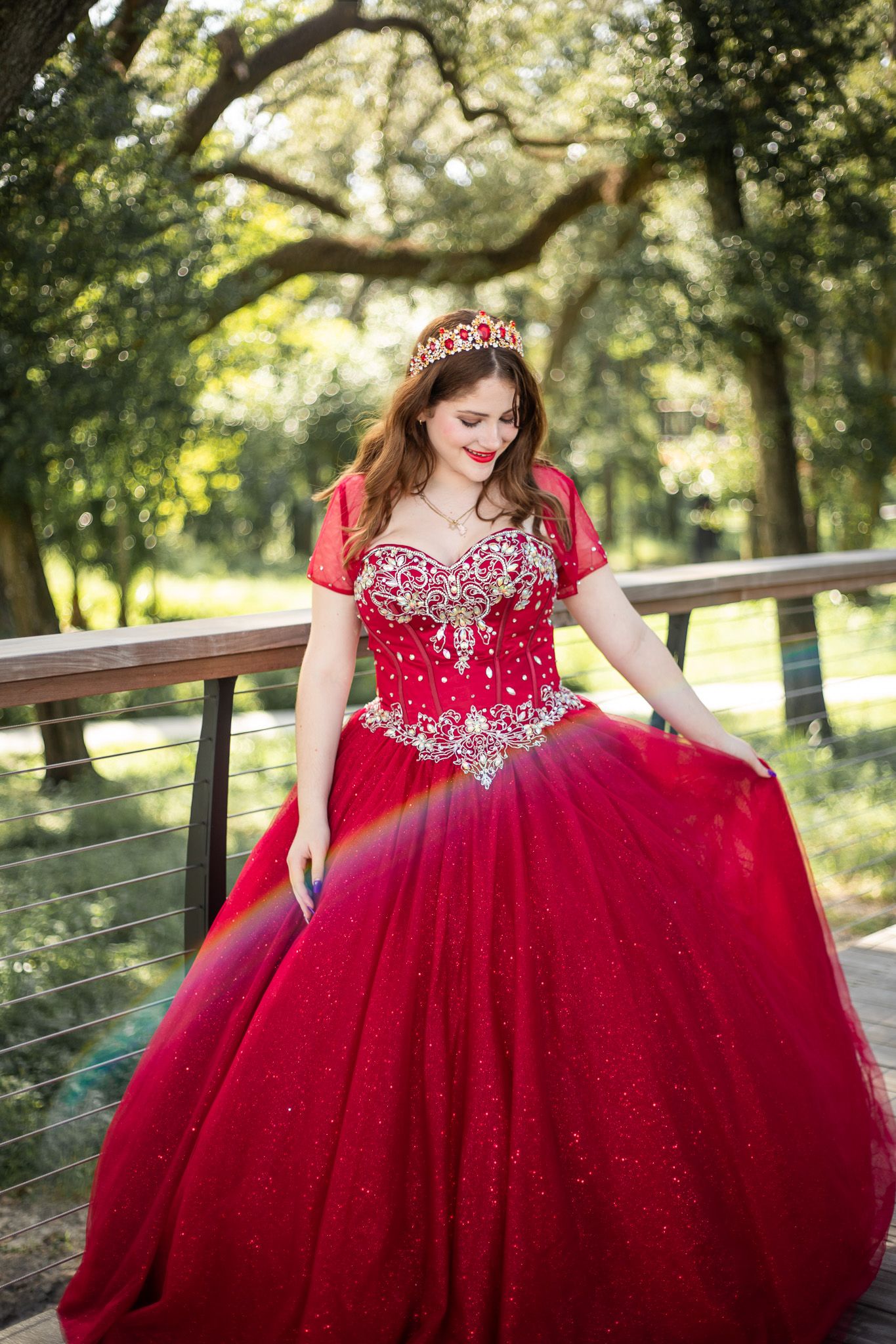 Elegant red ball gown with crystal bodice photographed in natural outdoor lighting.