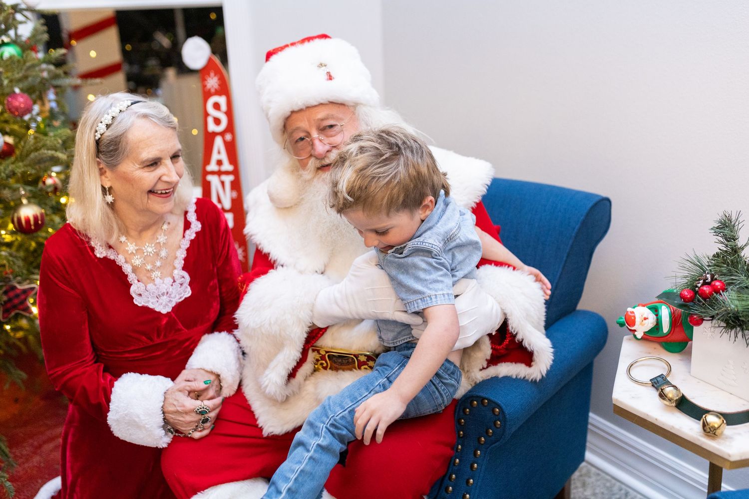 Holiday photo session with a baby and Santa in a festive red and white decorated setting.