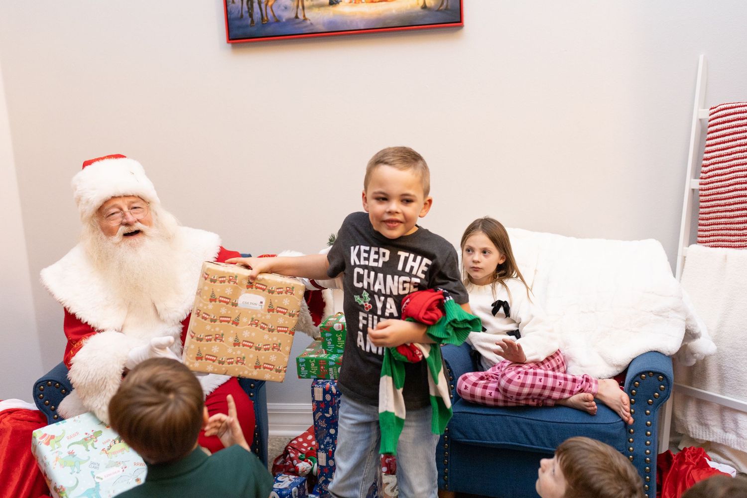 Children gather around Santa Claus during a festive holiday celebration with wrapped presents.