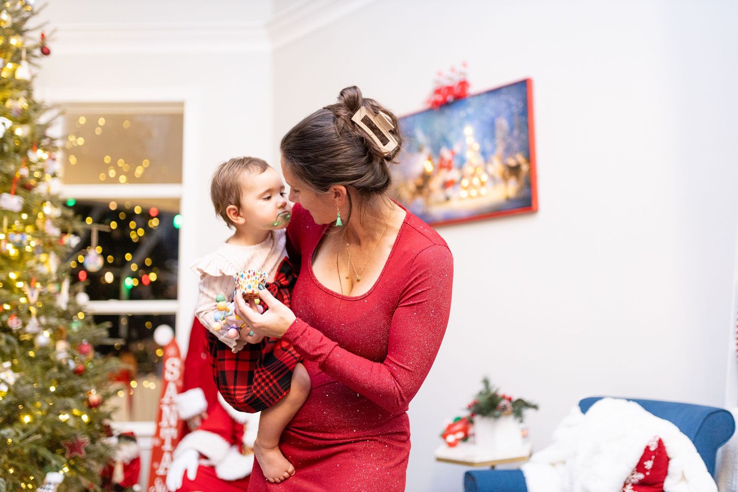 Festive Christmas scene with decorated tree and blue armchair in bright white room.