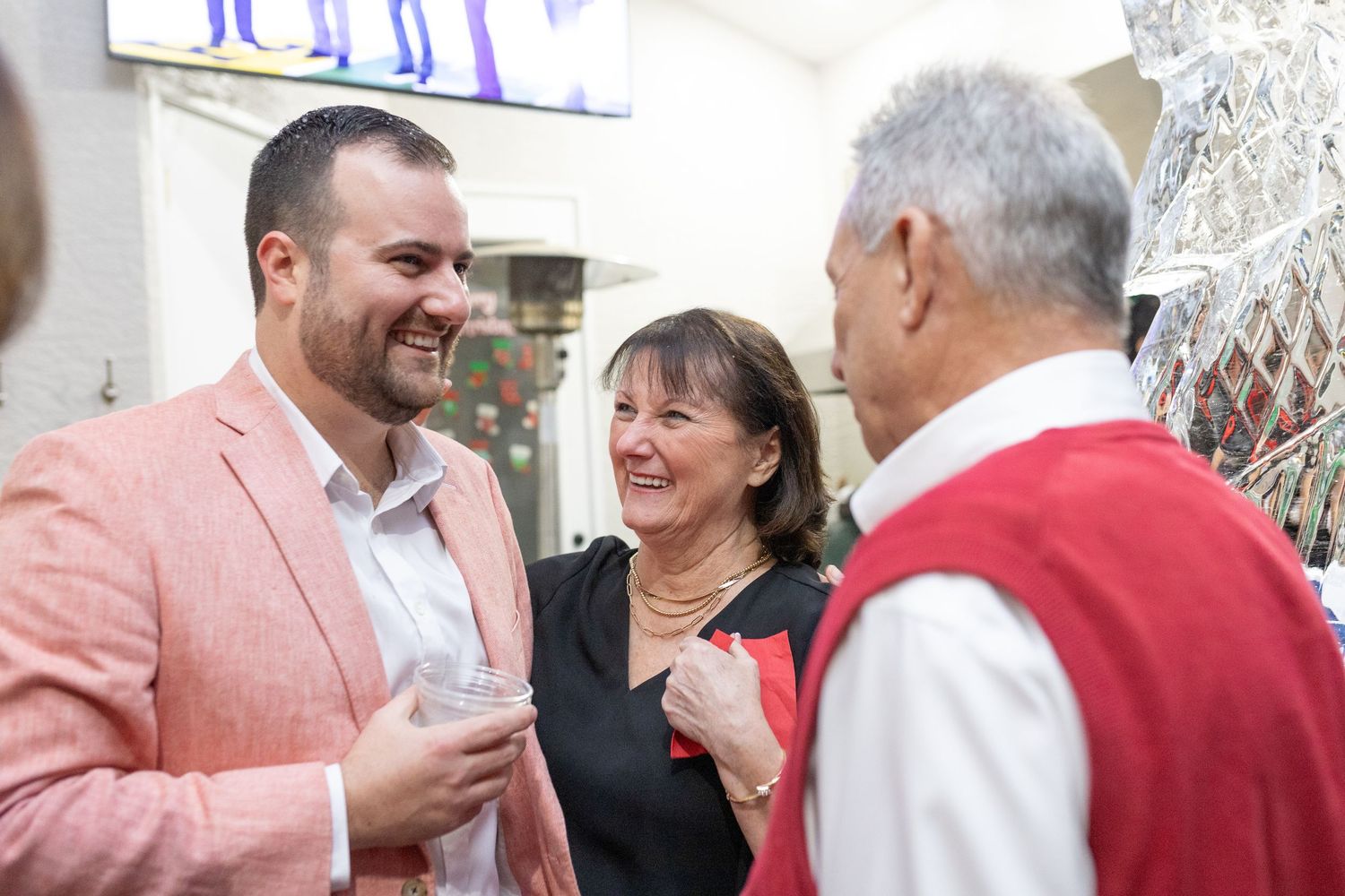 Festive holiday party scene with people mingling and laughing in a bright indoor space.