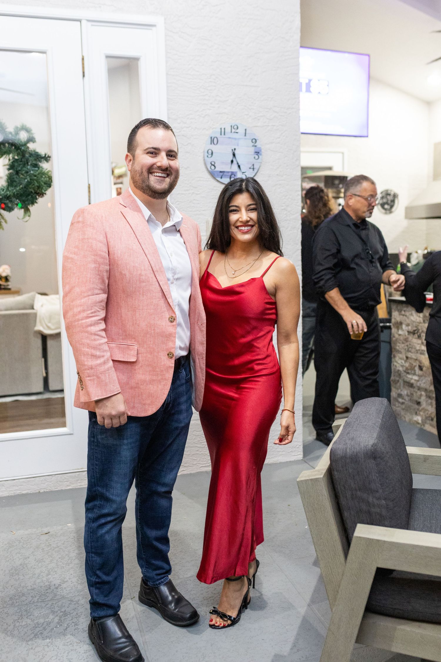 Couple at a party with person wearing pink blazer and red dress in an indoor venue.