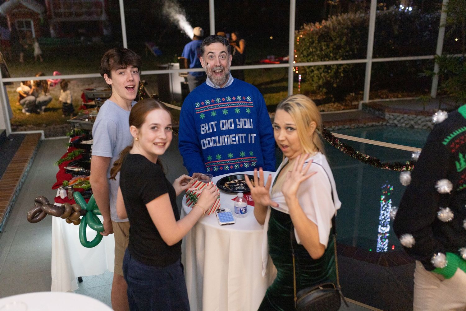 A group of people enjoying a nighttime holiday celebration with colorful lights.