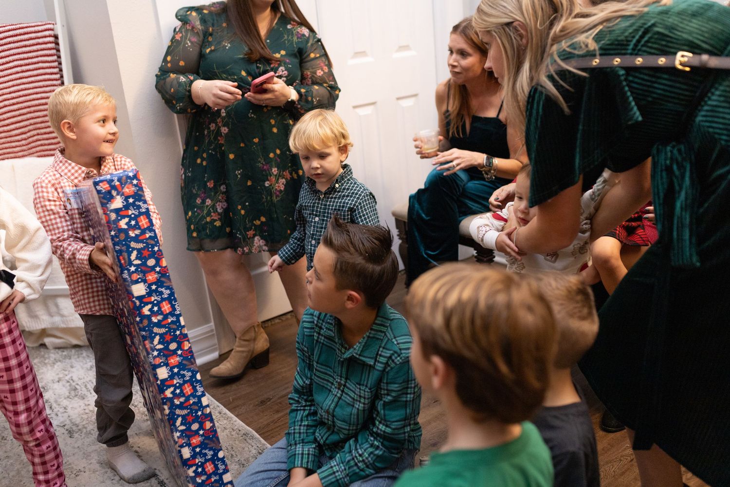 Group of people mingling at an indoor holiday gathering with Christmas decorations.
