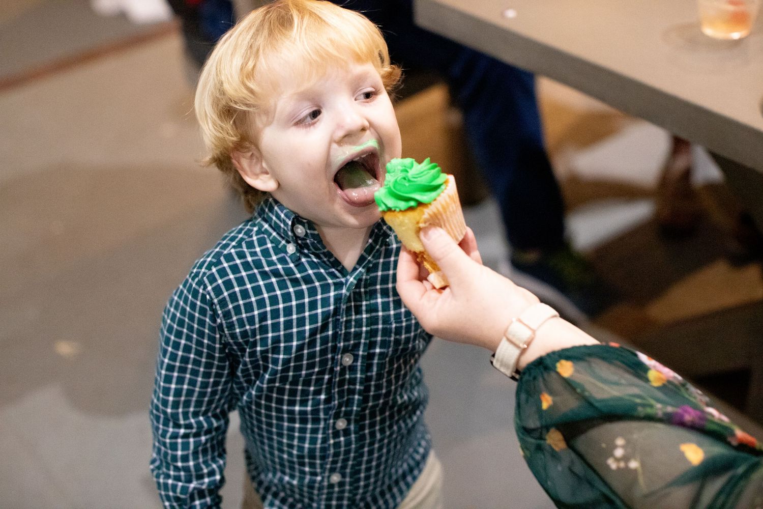 Young child in blue plaid shirt laughing and enjoying holiday treats at a celebration.