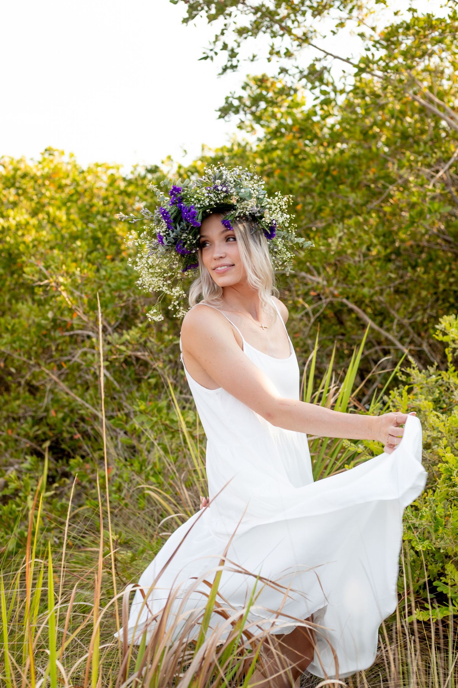 Playful outdoor portrait session with flowing white dress in natural setting.