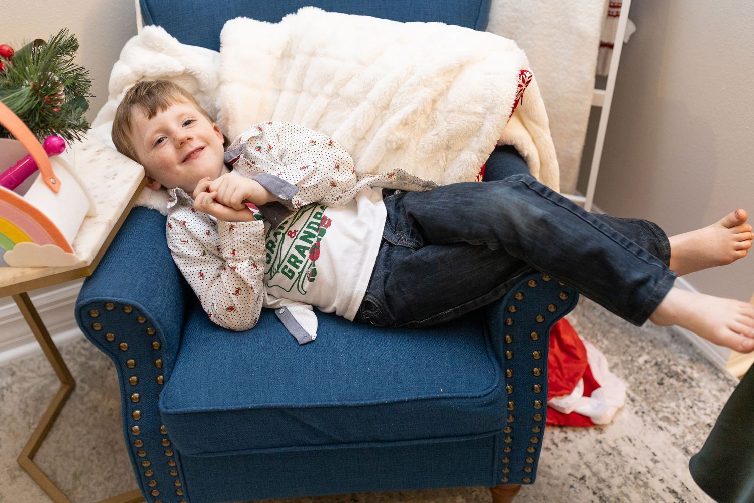 A child relaxes on a navy blue studded couch during holiday festivities.