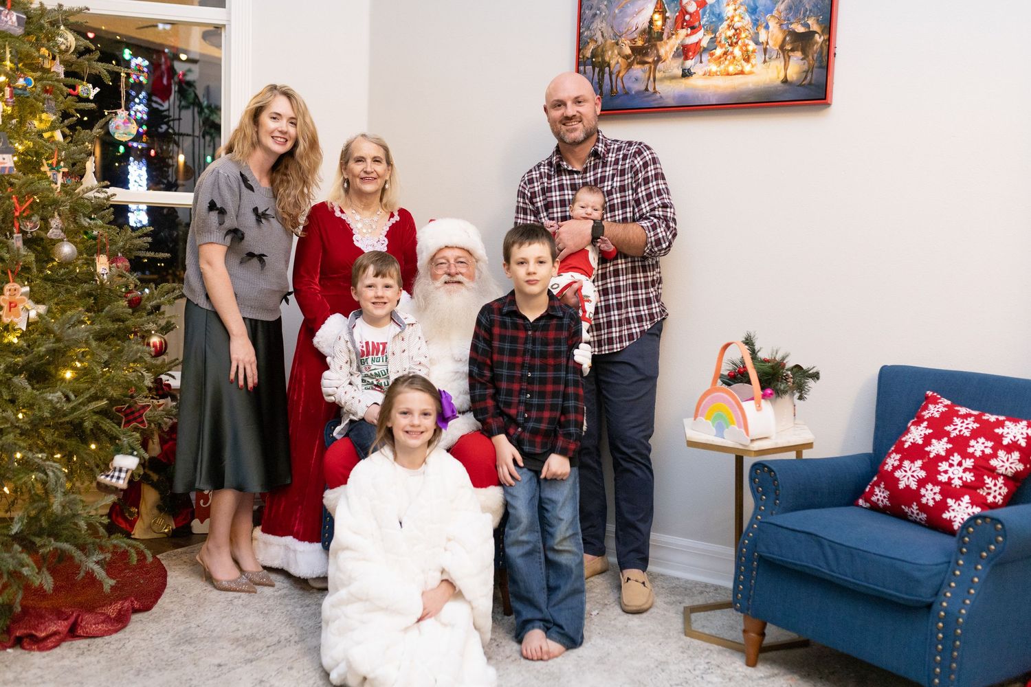 A holiday gathering with Christmas decorations and a blue couch in a bright room.